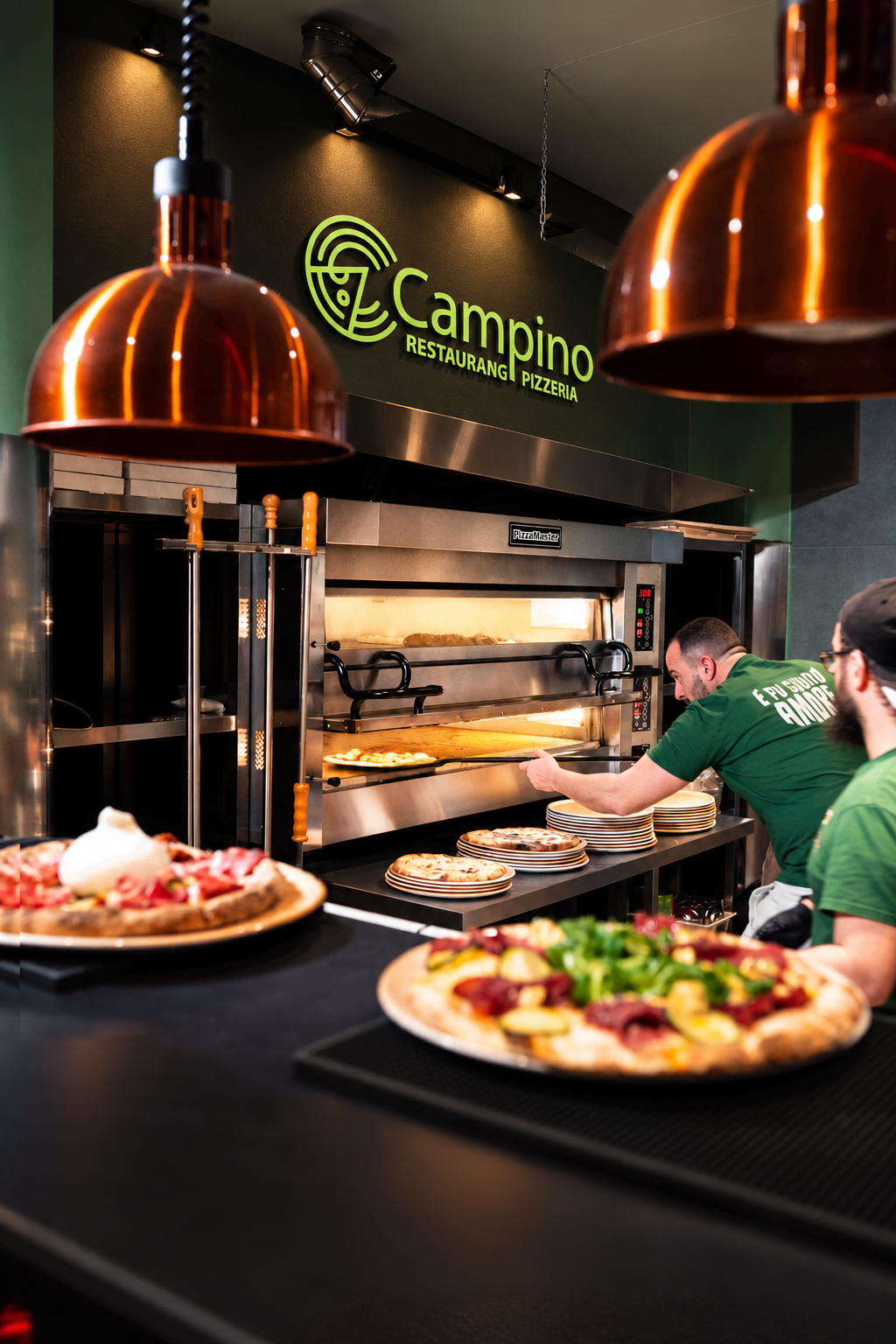 Pizzabagare tar ut en pizza ur ugnen i Campinos kök